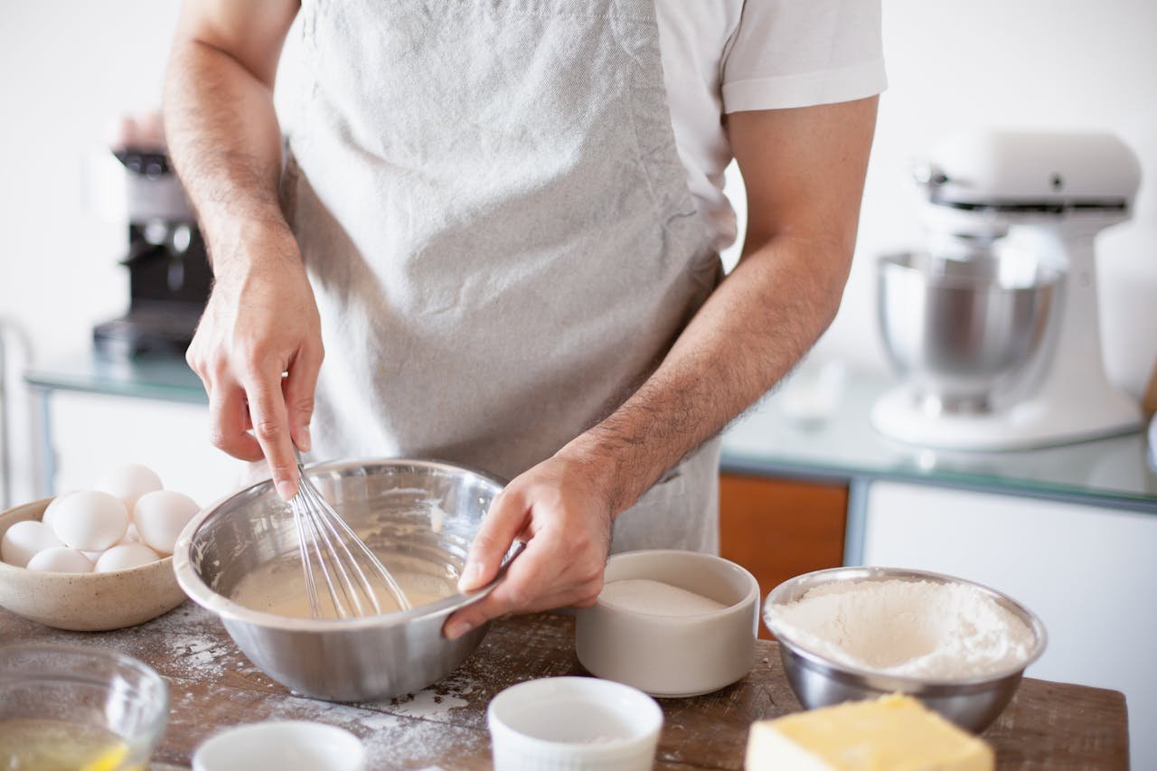Close-up of a person preparing batter with ingredients in a kitchen setting.